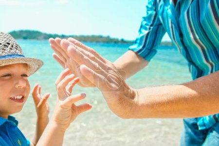 Téléchargez les photos : Mains d'un parent heureux et d'un enfant dans la nature au bord de la mer sur un fond de voyage - en image libre de droit