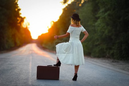 Téléchargez les photos : Vintage fille avec chapeau avec une valise auto-stop - en image libre de droit