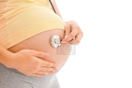 Foto de Mujer embarazada joven sobre un fondo blanco con estatoscopio - Imagen libre de derechos