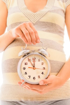 Photo for Beautiful young pregnant girl on a white background with alarm clock - Royalty Free Image