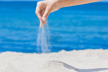 Téléchargez les photos : Les mains versent du sable de la mer sur la nature lors d'un voyage. Vacances en mer sable le temps passe. - en image libre de droit