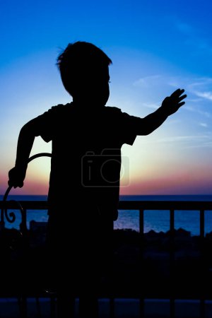 Photo for Happy child at the time of the silhouette of the sea background - Royalty Free Image