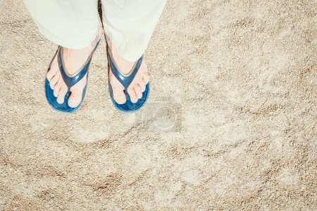 Foto de Hermosas piernas en zapatillas en el fondo de arena - Imagen libre de derechos