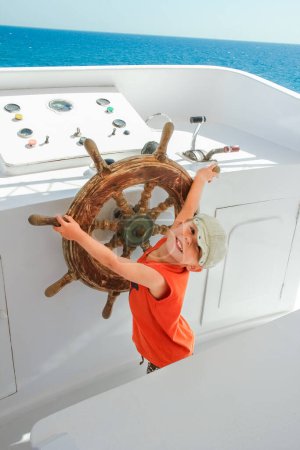 Photo for Happy child at the helm of the ship in the sea background - Royalty Free Image