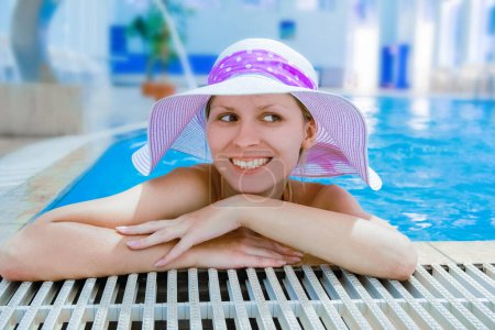 Foto de Un ventilador con sombrero se encuentra en una piscina de relajación. En un viaje - Imagen libre de derechos