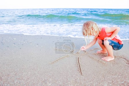 Foto de Niño feliz dibujar imágenes en la arena del mar en el verano en la naturaleza - Imagen libre de derechos