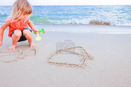 Foto de Niño feliz dibujar imágenes en la arena del mar en el verano en la naturaleza - Imagen libre de derechos