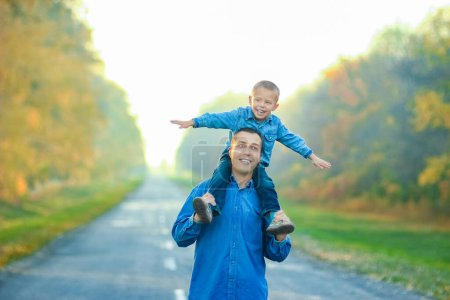 Foto de Padres felices con el niño están caminando a lo largo de la carretera en el parque en viaje por la naturaleza - Imagen libre de derechos