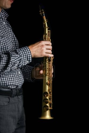 Photo for Soprano saxophone in hands on a black background - Royalty Free Image