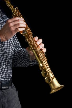 Foto de Saxofón soprano en manos sobre fondo negro - Imagen libre de derechos