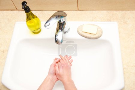 Foto de Las manos con jabón se lavan bajo el grifo con agua. Limpio de infección, suciedad y virus. En casa o en la oficina de ablución del hospital. - Imagen libre de derechos