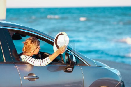 Téléchargez les photos : Fille heureuse dans la voiture par la mer dans la nature en voyage de vacances - en image libre de droit