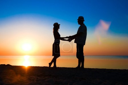 Téléchargez les photos : Joyeux couple au bord de la mer au coucher du soleil sur silhouette de voyage dans la nature - en image libre de droit