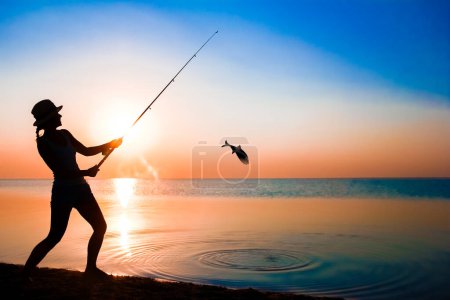 Photo for Happy girl fisherman catches fish by the sea on nature silhouette travel - Royalty Free Image