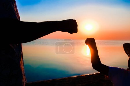 Téléchargez les photos : Mains de heureux père et enfant au bord de la mer sur la nature silhouette Voyage - en image libre de droit