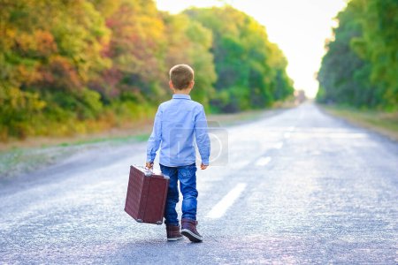 Photo for Happy child with a suitcase on the road in the park travel - Royalty Free Image
