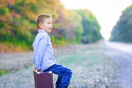Foto de Niño feliz con una maleta en la carretera en el parque de viaje - Imagen libre de derechos