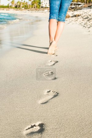 Téléchargez les photos : Belles traces avec pieds près de la mer sur fond de nature - en image libre de droit