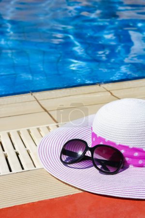 Photo for Beautiful hat near the pool with cream and glasses background - Royalty Free Image