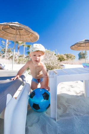 Téléchargez les photos : Enfant heureux jouant avec une balle près de la mer dans la nature - en image libre de droit