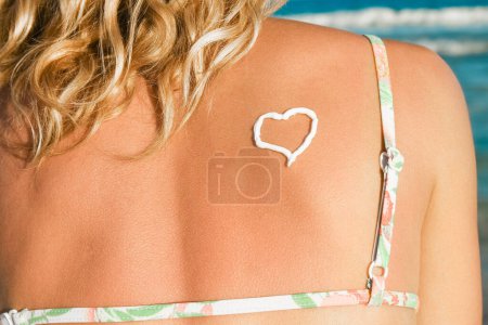 Photo for Happy girl with a heart on her back by the sea outdoors - Royalty Free Image