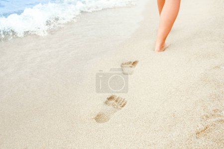 Photo for Beach travel - woman relaxing walking on a sandy beach leaving footprints in the sand. Close up detail of female feet on golden sand at a beach in Greece. Background. - Royalty Free Image