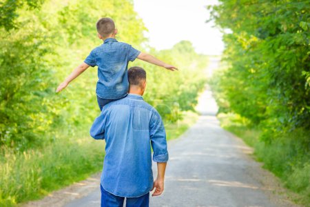 Photo for Happy child on the shoulders of a parent in nature on the way to travel - Royalty Free Image