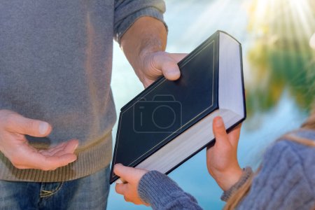 Téléchargez les photos : De main en main, un parent passe un livre à un enfant dans un parc en plein air voyage - en image libre de droit