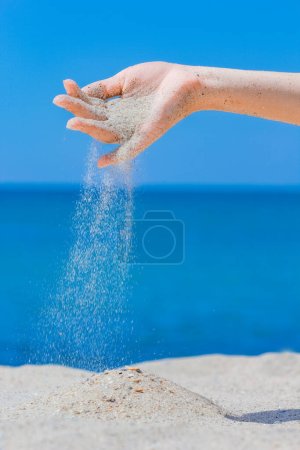 Téléchargez les photos : Mains versent du sable près de la mer - en image libre de droit