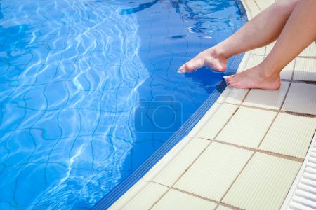 Téléchargez les photos : Belles jambes d'une fille près d'une piscine sur le fond de la mer - en image libre de droit
