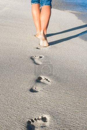 Téléchargez les photos : Belles traces avec pieds près de la mer sur fond de nature - en image libre de droit