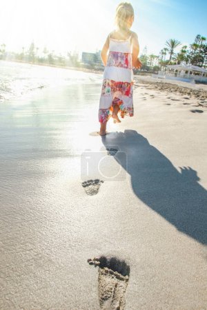 Téléchargez les photos : Belles empreintes de pas avec pieds sur le fond de sable - en image libre de droit