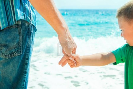 Foto de Hands of a happy parent and child on the seashore on a journey trip in nature - Imagen libre de derechos
