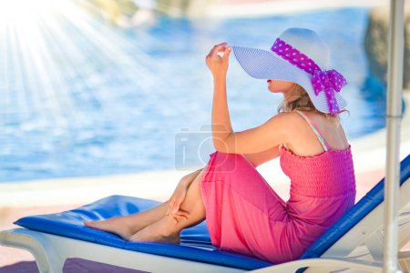Foto de Chica feliz en una tumbona junto a la piscina junto al mar - Imagen libre de derechos