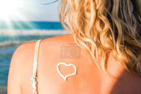 Téléchargez les photos : Fille heureuse avec un cœur sur le dos par la mer à l'extérieur - en image libre de droit