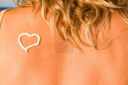 Photo for Happy girl with a heart on her back by the sea outdoors - Royalty Free Image