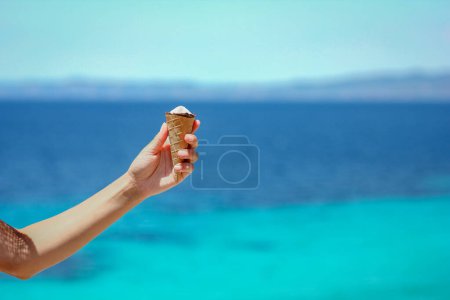 Téléchargez les photos : Crème glacée dans les mains près du bord de mer dans la nature week-end Voyage - en image libre de droit