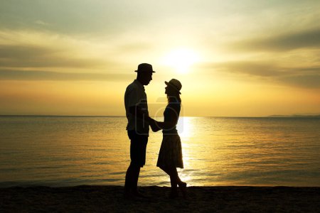 Téléchargez les photos : Couple heureux au bord de la mer sur la nature en silhouette de voyage - en image libre de droit