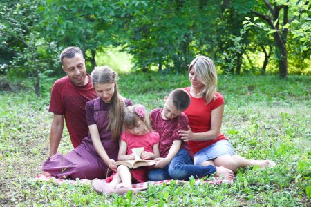 Photo for Happy family reading bible book in nature concept faith christianity - Royalty Free Image
