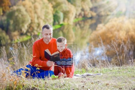 Téléchargez les photos : Père et enfant lisant le livre Bible sur la nature concept foi espoir famille - en image libre de droit