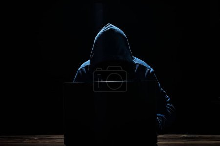 Photo for Hacker with laptop sits at a table and abstract binary code. Business life threat virtual programs. - Royalty Free Image
