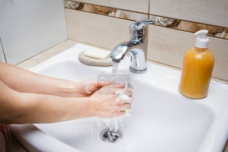 Téléchargez les photos : Les mains avec du savon sont lavées sous le robinet avec de l'eau. Nettoyer de l'infection et la saleté et le virus. À la maison ou au bureau d'ablution de l'hôpital. - en image libre de droit