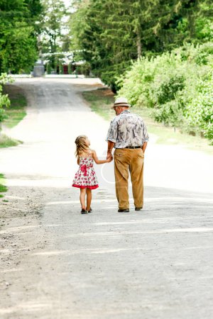 Téléchargez les photos : Grand-père et petite-fille marchant le long de la route - en image libre de droit