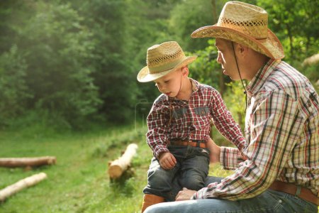 Téléchargez les photos : Enfant heureux avec parent cow-boy dans la nature dans le domaine - en image libre de droit