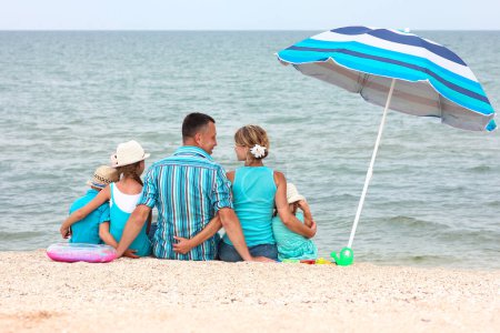 Téléchargez les photos : Joyeux famille jouant au bord de la mer sur le fond de sable - en image libre de droit