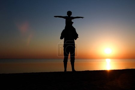 Téléchargez les photos : Joyeux parent avec enfant au bord de la mer jouer sur la nature silhouette Voyage - en image libre de droit
