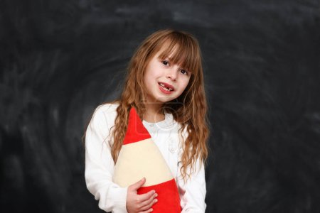 Photo for Happy little girl student emotions with a big pencil on black background - Royalty Free Image