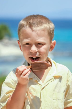 Téléchargez les photos : Heureux enfant garçon avec de la crème glacée au bord de la mer dans la nature dans le voyage du parc - en image libre de droit