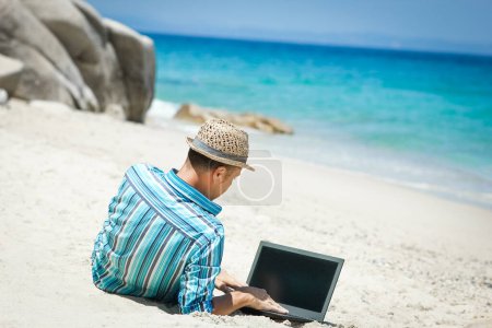 Foto de Happy man guy with laptop near the seashore weekend travel - Imagen libre de derechos