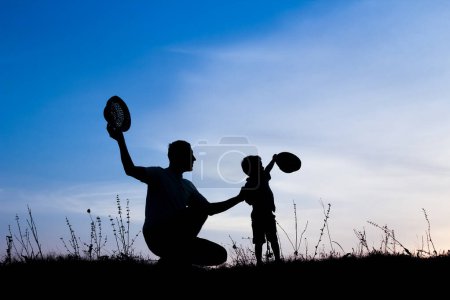 Foto de Padres felices con niños jugando en la silueta de verano de la naturaleza - Imagen libre de derechos